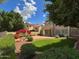 Charming backyard featuring green lawn, brick patio, fountain, colorful flowers, and well-maintained landscaping at 21538 N 59Th Ln, Glendale, AZ 85308