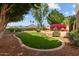 Charming backyard featuring green lawn, brick patio, fountain, colorful flowers, and well-maintained landscaping at 21538 N 59Th Ln, Glendale, AZ 85308