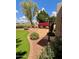 Charming backyard featuring green lawn, brick patio, fountain, colorful flowers, and well-maintained landscaping at 21538 N 59Th Ln, Glendale, AZ 85308