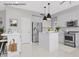 Staged modern kitchen with stainless steel appliances, a central island, and sleek white cabinets at 21538 N 59Th Ln, Glendale, AZ 85308