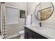 Modern bathroom featuring a vanity with a sleek black faucet, round mirror, and tiled shower at 22036 N 44Th Pl, Phoenix, AZ 85050
