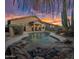 Sparkling backyard pool and desert landscape with rock water feature at sunset at 22036 N 44Th Pl, Phoenix, AZ 85050