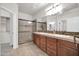 Well-lit bathroom with double sinks, wooden cabinets, and glass-enclosed shower at 27614 N 129Th Ln, Peoria, AZ 85383
