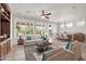 Bright living room featuring tan sofas with blue pillows, a ceiling fan and large windows with white shutters at 27614 N 129Th Ln, Peoria, AZ 85383