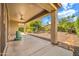 Covered patio leading to a desert landscaped backyard with mature trees at 27614 N 129Th Ln, Peoria, AZ 85383