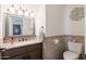 Well-lit half bath featuring a granite countertop, decorative mirror, and tiled accents at 29431 N 23Rd Dr Dr, Phoenix, AZ 85085