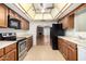 Traditional-style kitchen features wooden cabinets, tile floors, and black appliances at 3345 E University Dr # 73, Mesa, AZ 85213