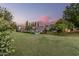 A backyard, bathed in the sunset, with a green lawn, sparkling pool, and mature trees at 370 E Redfield Rd, Chandler, AZ 85225