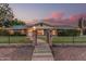 Charming home featuring a brick pathway, iron gate, lush lawn, and mature trees at dusk at 370 E Redfield Rd, Chandler, AZ 85225