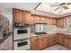 Kitchen with wood cabinets, dual oven, cooktop, and access to the living room fireplace at 370 E Redfield Rd, Chandler, AZ 85225