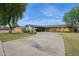 Single story brick home with a circular driveway, mature trees, lush green lawns, and attached carport at 4408 N 28Th Pl, Phoenix, AZ 85016