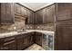 Elegant bar area with dark wood cabinetry, a beverage refrigerator, and stone backsplash at 447 W Judd Rd, San Tan Valley, AZ 85143