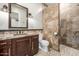 Bathroom with granite countertop, wood cabinets, stone-look shower and pebble flooring at 447 W Judd Rd, San Tan Valley, AZ 85143