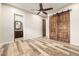 Bedroom with barn door leading to bathroom featuring wood-look flooring and ceiling fan at 447 W Judd Rd, San Tan Valley, AZ 85143