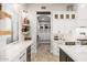 A modern kitchen with shelving, marble countertops, white cabinets, stainless appliances, and an arched doorway at 447 W Judd Rd, San Tan Valley, AZ 85143