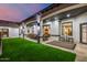 A covered patio features turf lawn, an outdoor dining area and living space with a fireplace at 447 W Judd Rd, San Tan Valley, AZ 85143