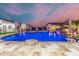 Beautiful pool with travertine tile and integrated rock features, set against a picturesque twilight sky at 447 W Judd Rd, San Tan Valley, AZ 85143