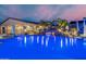 Lush backyard pool area with a rock waterfall and palm trees, enhanced by ambient lighting at 447 W Judd Rd, San Tan Valley, AZ 85143