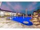 Stunning pool with waterfall feature and travertine tile, surrounded by lush landscaping and a house in the background at 447 W Judd Rd, San Tan Valley, AZ 85143