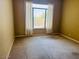 An empty bedroom features light yellow walls, carpet, and bright window at 4843 E Estevan Rd, Phoenix, AZ 85054