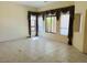 An empty living room features tan walls, tile floors, and large windows with brown curtains at 4843 E Estevan Rd, Phoenix, AZ 85054