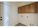 This laundry room includes wooden cabinets, tile floors, and washer and dryer hookups at 507 W Magdalena Ln, Phoenix, AZ 85041