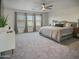 Spacious carpeted bedroom features a comfortable gray bed, a ceiling fan and three windows with decorative curtains at 5110 E Peak View Rd, Cave Creek, AZ 85331