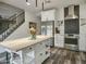 Bright kitchen featuring an island, stainless steel appliances, white cabinets, and dark wood-look flooring with access to a staircase at 5110 E Peak View Rd, Cave Creek, AZ 85331