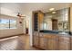 Entertaining bar area featuring wood cabinets, a mirrored backsplash, a sink, and a ceiling fan at 6252 E Aire Libre Ln, Scottsdale, AZ 85254
