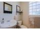 Bright bathroom featuring a vessel sink, toilet, vanity mirror, and glass block window providing natural light at 6936 E Whispering Mesquite Trl, Scottsdale, AZ 85266
