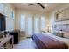 Cozy bedroom features a ceiling fan, bedside table with lamp, tile floors, and access to the outdoors through white french doors at 6936 E Whispering Mesquite Trl, Scottsdale, AZ 85266