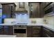 Gourmet kitchen with stainless steel stove, textured backsplash, and custom cabinetry at 6936 E Whispering Mesquite Trl, Scottsdale, AZ 85266