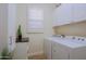 Bright laundry room with front loading washer and dryer, white cabinets and plantation shutters at 6936 E Whispering Mesquite Trl, Scottsdale, AZ 85266
