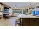 Spacious living area with stone fireplace, kitchen island, and views of the backyard and desert landscape at 6936 E Whispering Mesquite Trl, Scottsdale, AZ 85266