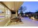 Covered patio features outdoor seating, fireplace, manicured landscaping, and hill views at sunset at 6936 E Whispering Mesquite Trl, Scottsdale, AZ 85266