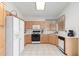 Bright kitchen features tile floors, a skylight, and wooden cabinets with white countertops and appliances at 9032 W Sierra Pinta Dr, Peoria, AZ 85382