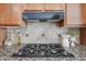 Close up image of a gas cooktop featuring stainless steel accents and granite countertops at 9698 S 183Rd Ave, Goodyear, AZ 85338