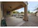 Covered patio overlooking a backyard with a rock feature, plants, and blue umbrellas at 9698 S 183Rd Ave, Goodyear, AZ 85338