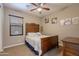Bedroom showcasing a wooden bed frame, ceiling fan, window with blinds, and carpet flooring at 10846 E Quartet Ave, Mesa, AZ 85212
