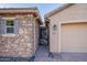 Close-up of home's entry with stone accents, decorative iron gate and security door, and a side-entry two-car garage at 10846 E Quartet Ave, Mesa, AZ 85212