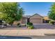 Charming single-story home featuring desert landscaping, lush trees, and a paver driveway leading to a spacious two-car garage at 10846 E Quartet Ave, Mesa, AZ 85212