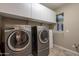 Laundry room with gray front load washer and dryer, white cabinets, and natural light at 10846 E Quartet Ave, Mesa, AZ 85212