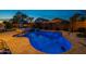 Backyard oasis with pool, spa, lounge area, and lush landscaping illuminated at twilight at 10846 E Quartet Ave, Mesa, AZ 85212