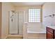 Bright bathroom featuring a glass enclosed shower and soaking tub with a glass block window for natural light at 14214 W Ventura St, Surprise, AZ 85379