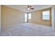 Bedroom with light walls, neutral carpet, ceiling fan and two windows at 14214 W Ventura St, Surprise, AZ 85379