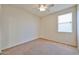 This bedroom features carpet flooring, a ceiling fan and a large window at 14214 W Ventura St, Surprise, AZ 85379