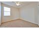 This bedroom features carpet flooring, a ceiling fan and a large window at 14214 W Ventura St, Surprise, AZ 85379