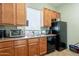Functional kitchenette with wooden cabinets, stainless steel sink, black appliances, and a window at 16013 S Desert Foothills Pkwy # 2055, Phoenix, AZ 85048