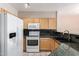 Bright kitchen featuring wooden cabinets, granite countertops, white appliances, and tile flooring at 16616 E Gunsight Dr # 114, Fountain Hills, AZ 85268