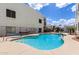 Community swimming pool area featuring lounge chairs, fencing, and surrounding buildings under a blue sky at 16616 E Gunsight Dr # 114, Fountain Hills, AZ 85268